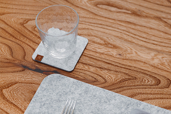 Glasuntersetzer aus Filz in Hellgrau auf einem Holztisch